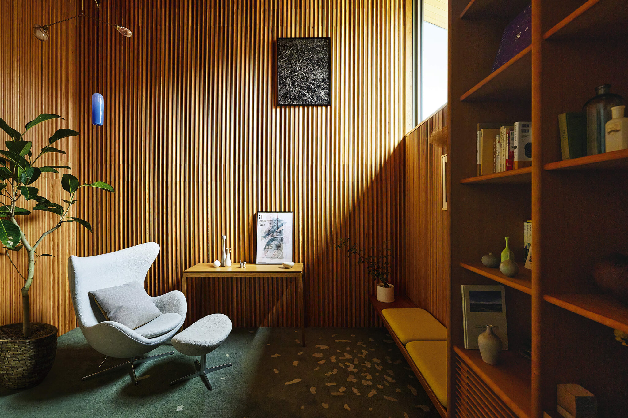木格子の壁と観葉植物が印象的な落ち着いた書斎スペース。デザイナーズチェアのある洗練された空間