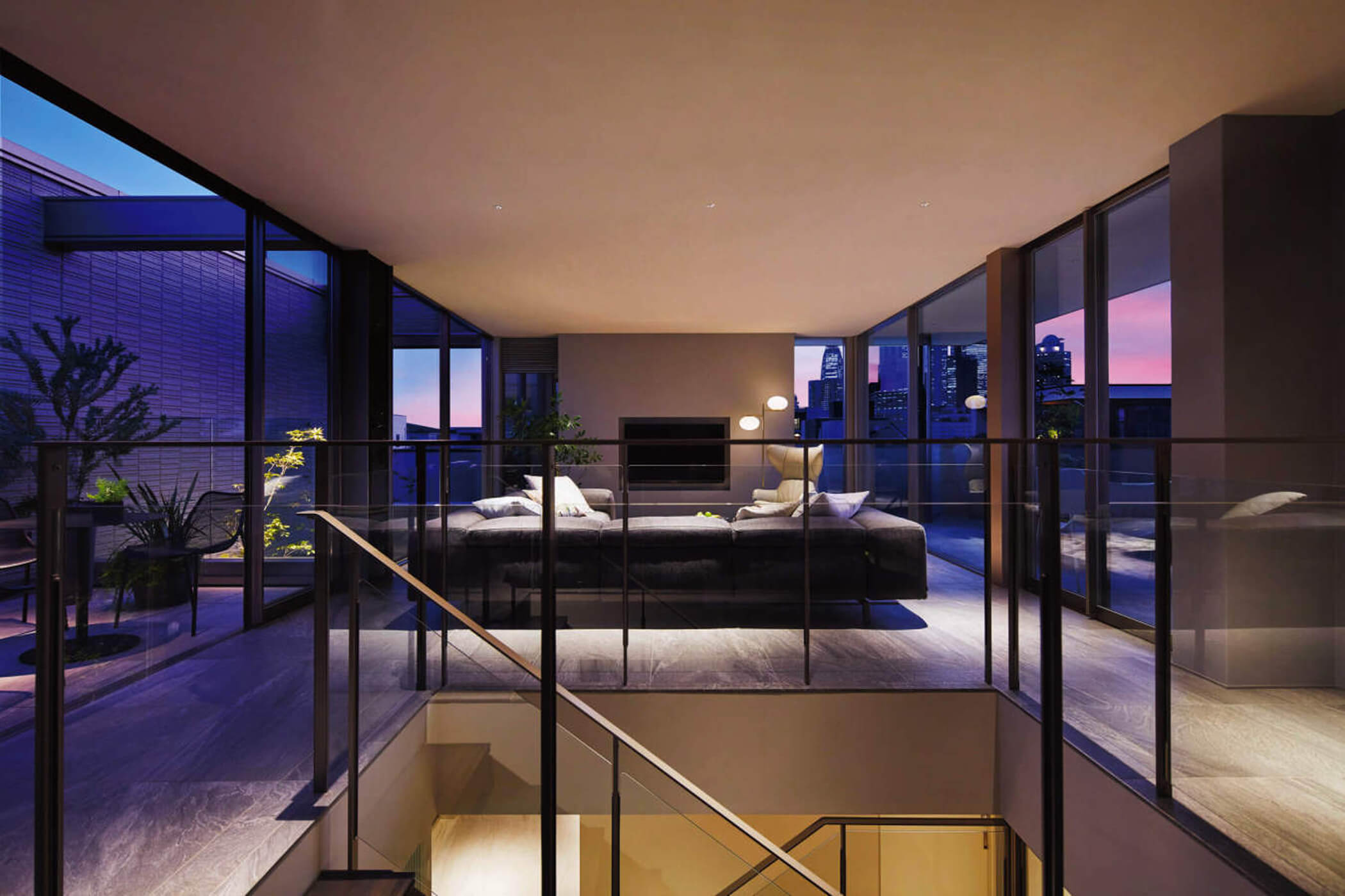 夕暮れ時のガラス張りリビング。屋外テラスとつながる開放的な空間デザイン