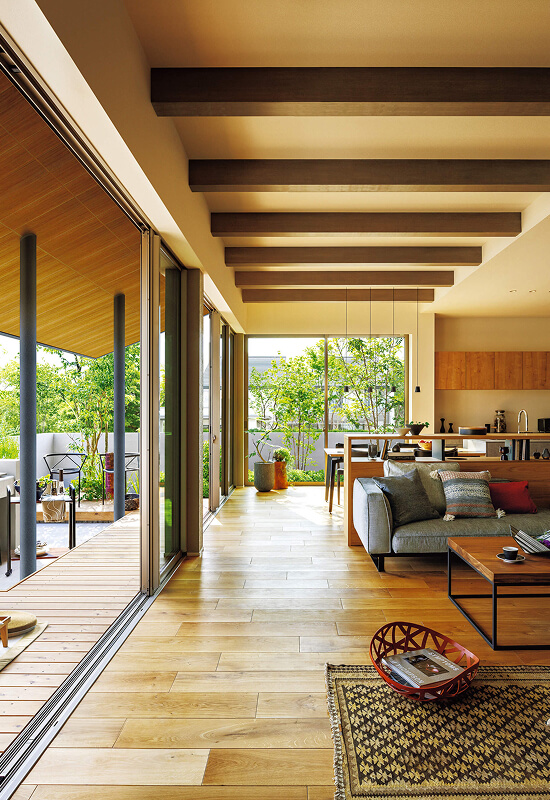 ウッドデッキテラスとつながるリビングダイニング。梁見せ天井と開放的な室内外一体空間