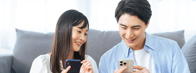 スマートフォンで相談予約をする若いカップル。WEBから簡単に予約できる様子